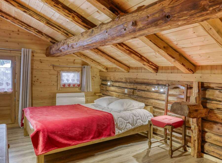Step into rustic charm with this cozy bedroom featuring exposed wooden beams and a warm, inviting atmosphere.