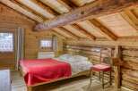 Step into rustic charm with this cozy bedroom featuring exposed wooden beams and a warm, inviting atmosphere.
