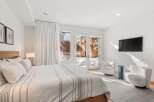 This stunning bedroom boasts a serene ambiance with its neutral color palette and ample natural light.