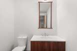 This modern bathroom features a sleek design with a wooden vanity and a pristine white countertop.