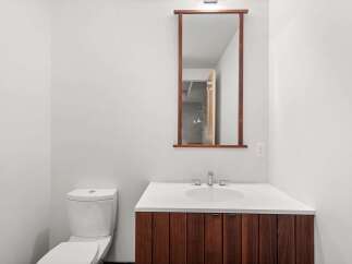 This modern bathroom features a sleek design with a wooden vanity and a pristine white countertop.