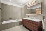 This modern bathroom features a sleek design with a large wooden vanity and a matching mirror frame.