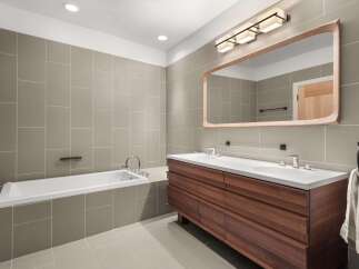 This modern bathroom features a sleek design with a large wooden vanity and a matching mirror frame.