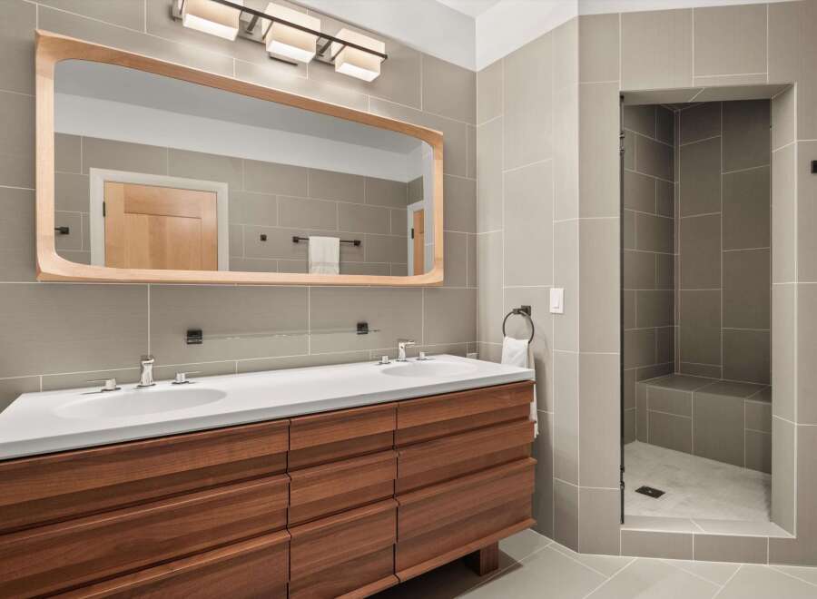 This modern bathroom boasts a sleek design with a double vanity and a walk-in shower.