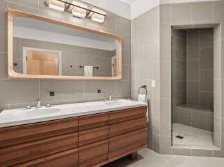 This modern bathroom boasts a sleek design with a double vanity and a walk-in shower.