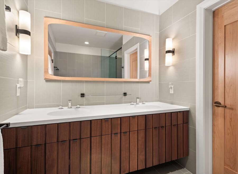 This modern bathroom boasts a sleek design with a wooden vanity and a large mirror.