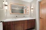 This modern bathroom boasts a sleek design with a wooden vanity and a large mirror.