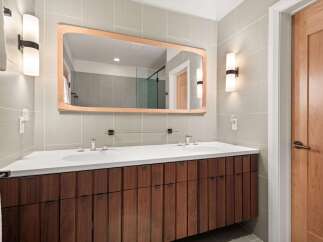 This modern bathroom boasts a sleek design with a wooden vanity and a large mirror.