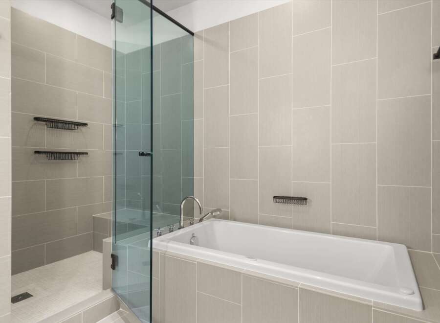 Step into luxury with this stunning bathroom featuring a sleek glass shower enclosure and a modern soaking tub.
