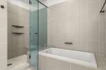 Step into luxury with this stunning bathroom featuring a sleek glass shower enclosure and a modern soaking tub.