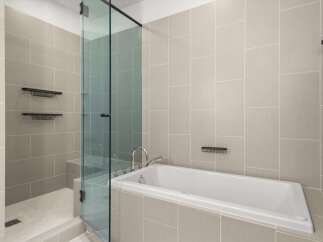 Step into luxury with this stunning bathroom featuring a sleek glass shower enclosure and a modern soaking tub.