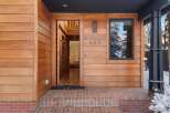 This stunning property features a welcoming entrance with a wooden facade and a modern design.