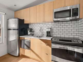 This modern kitchen boasts sleek, light wood cabinetry and stainless steel appliances, creating a bright and inviting space.