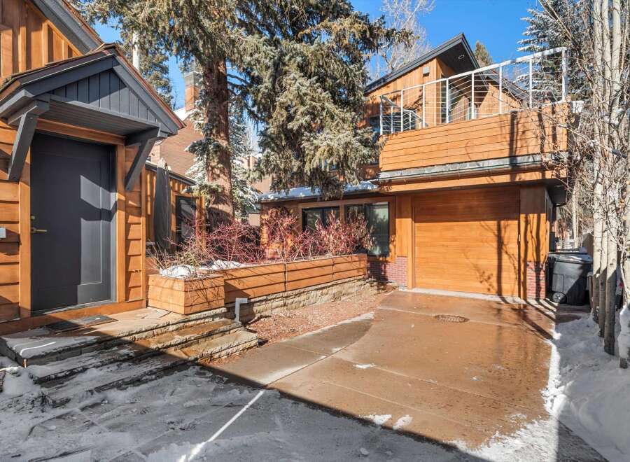 This stunning property boasts a modern design with beautiful wooden siding and a sleek, dark-colored door.