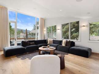 Experience breathtaking mountain views from this stunning living room, featuring a spacious sectional sofa and a modern coffee table.