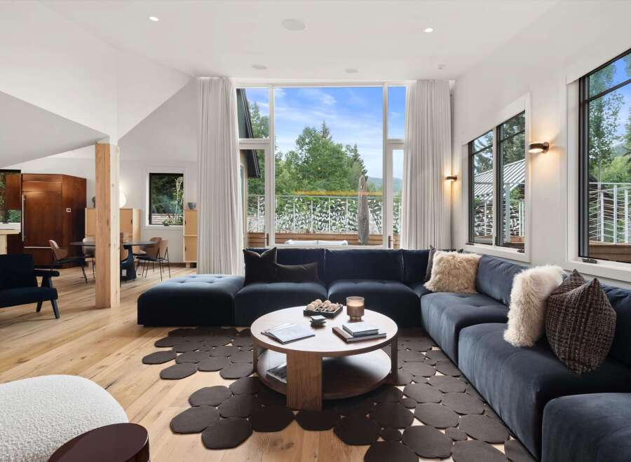 Experience modern living in this stunning home featuring a spacious sectional sofa and a unique, organic-shaped rug.
