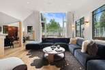 Experience modern living in this stunning home featuring a spacious sectional sofa and a unique, organic-shaped rug.