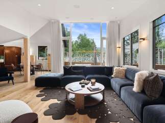 Experience modern living in this stunning home featuring a spacious sectional sofa and a unique, organic-shaped rug.