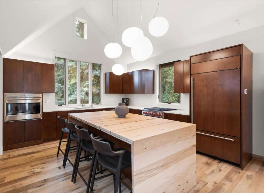 Experience modern luxury in this stunning kitchen, featuring rich wood cabinetry and a striking waterfall island.