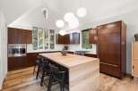 Experience modern luxury in this stunning kitchen, featuring rich wood cabinetry and a striking waterfall island.