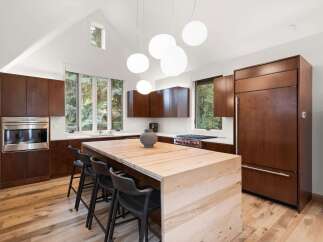 Experience modern luxury in this stunning kitchen, featuring rich wood cabinetry and a striking waterfall island.