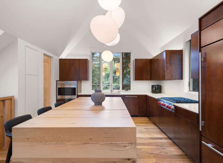 Experience modern luxury in this stunning kitchen, featuring rich wood cabinetry and a substantial light wood island perfect for gathering.