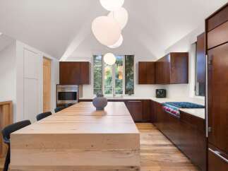 Experience modern luxury in this stunning kitchen, featuring rich wood cabinetry and a substantial light wood island perfect for gathering.