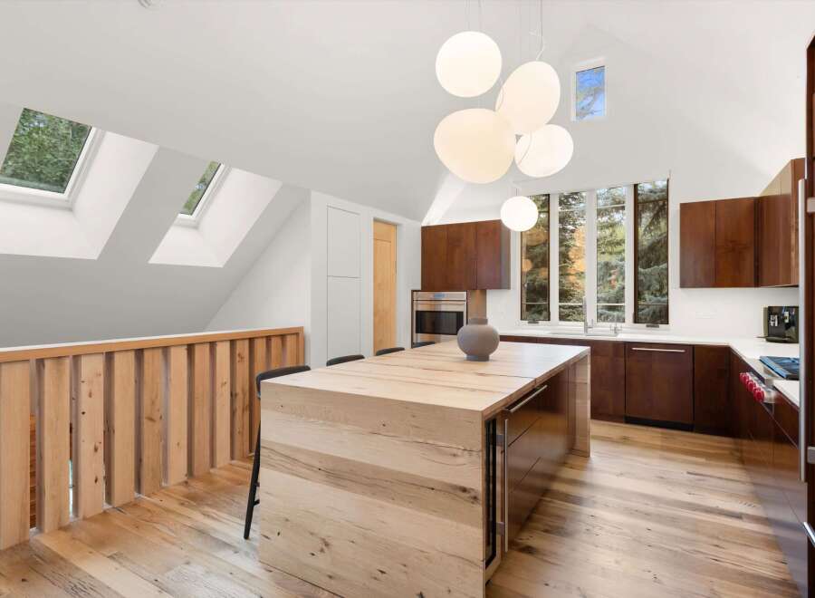 Experience modern living in this stunning kitchen featuring a large wooden island perfect for gatherings and a sleek, dark wood cabinetry.