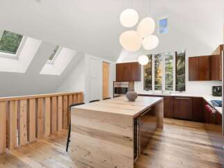 Experience modern living in this stunning kitchen featuring a large wooden island perfect for gatherings and a sleek, dark wood cabinetry.