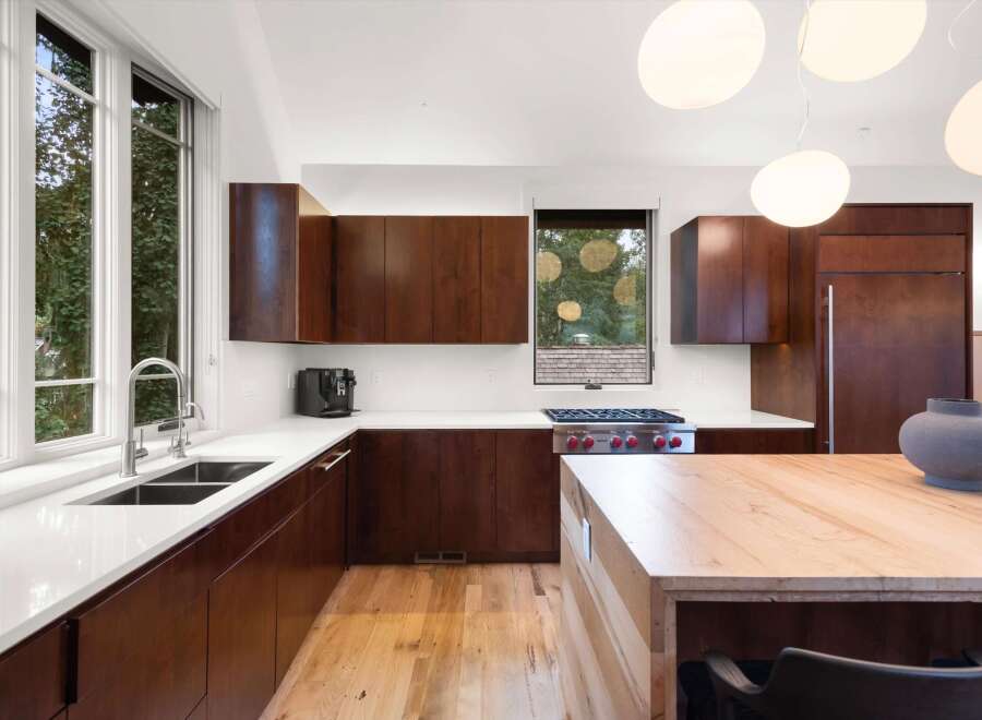 Experience modern luxury in this stunning kitchen featuring rich wood cabinetry and sleek white countertops.