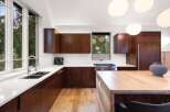Experience modern luxury in this stunning kitchen featuring rich wood cabinetry and sleek white countertops.
