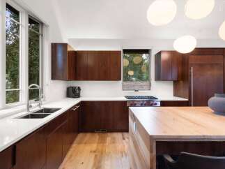 Experience modern luxury in this stunning kitchen featuring rich wood cabinetry and sleek white countertops.
