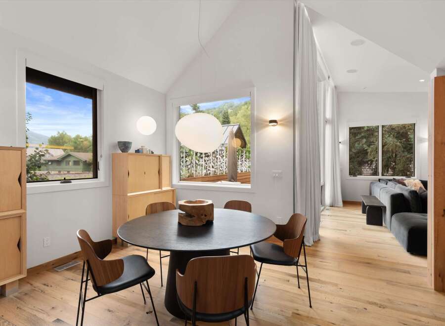 Experience modern living in this stunning dining area, featuring a sleek black round table surrounded by elegant wood and black chairs.