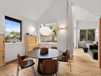Experience modern living in this stunning dining area, featuring a sleek black round table surrounded by elegant wood and black chairs.