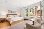 Experience luxurious comfort in this master bedroom, featuring a king-sized bed with plush bedding and a modern wooden headboard.