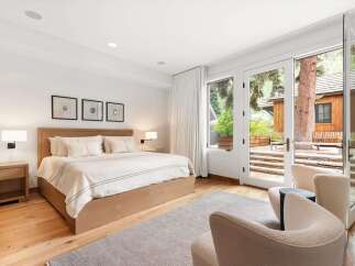 Experience luxurious comfort in this master bedroom, featuring a king-sized bed with plush bedding and a modern wooden headboard.