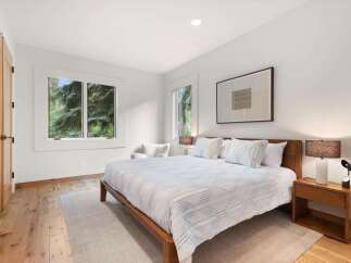Experience tranquility in this serene bedroom, featuring a comfortable king-size bed adorned with crisp white linens and accent pillows.