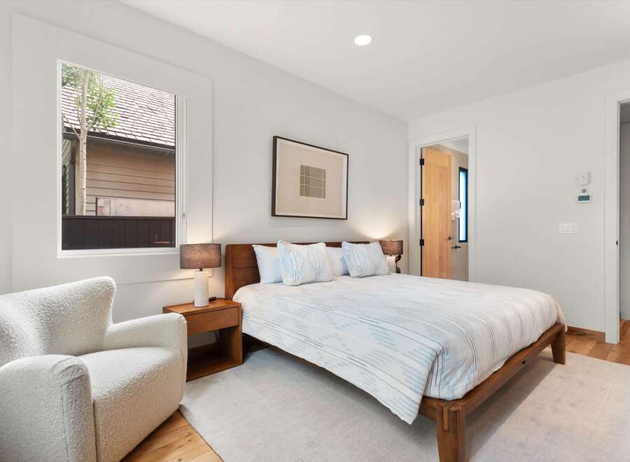 Experience modern comfort in this serene bedroom, featuring a plush white armchair perfect for relaxation.