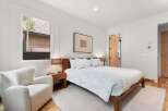 Experience modern comfort in this serene bedroom, featuring a plush white armchair perfect for relaxation.
