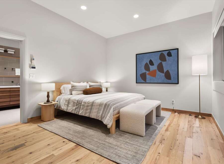 Experience modern comfort in this beautifully appointed bedroom, featuring a plush king-size bed adorned with striped linens and decorative pillows.
