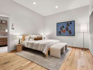Experience modern comfort in this beautifully appointed bedroom, featuring a plush king-size bed adorned with striped linens and decorative pillows.