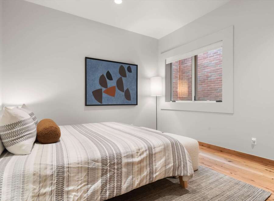 Experience comfort and style in this beautifully appointed bedroom, featuring a plush bed adorned with decorative pillows and a striped duvet.