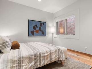Experience comfort and style in this beautifully appointed bedroom, featuring a plush bed adorned with decorative pillows and a striped duvet.