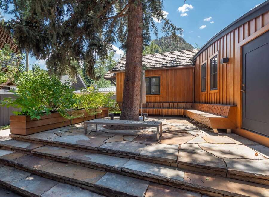 Experience seamless indoor-outdoor living with this stunning patio featuring natural stone paving and a built-in wooden bench.