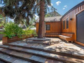 Experience seamless indoor-outdoor living with this stunning patio featuring natural stone paving and a built-in wooden bench.