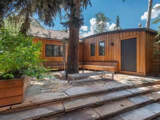 Experience outdoor living at its finest with this charming patio space, featuring natural stone steps and a built-in wooden bench perfect for enjoying the serene surroundings.