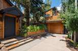 Experience modern mountain living in this stunning home featuring a sleek dark entryway with natural wood siding and stone steps.