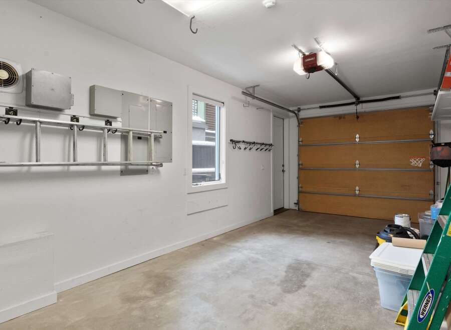 This spacious garage offers ample storage solutions, including a ladder rack and wall hooks, perfect for organizing tools and equipment.
