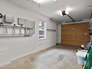 This spacious garage offers ample storage solutions, including a ladder rack and wall hooks, perfect for organizing tools and equipment.