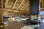 Experience luxury living in this stunning chalet, featuring a cozy living area with a fireplace and wooden beams.